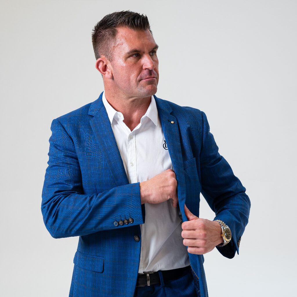Professional man in a blue suit adjusting his cuff, with a testimonial from Nathan James, Founder of Fitness Cartel AUS, praising Jakob's diligent work on fitness club projects.