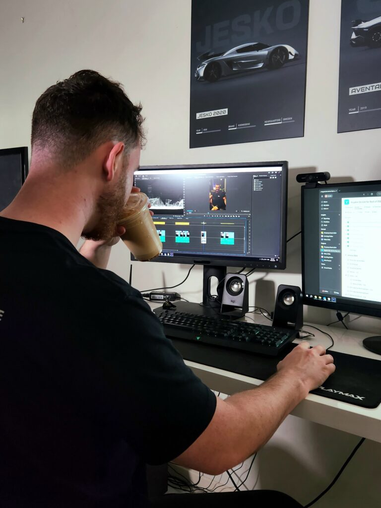 Content creator sipping coffee while editing a video project on a dual monitor setup, showcasing the post-production phase of content creation