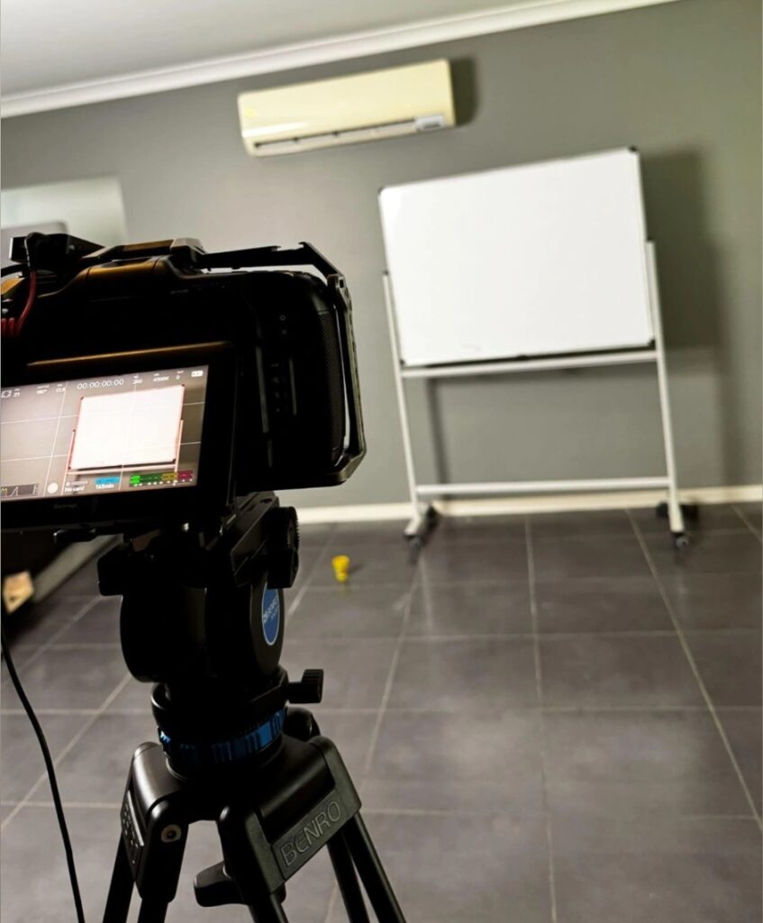 Digital content creation setup with camera on tripod focusing on a whiteboard in a well-lit room, illustrating the process of content development for social media and marketing strategies answering 'How do I create content?