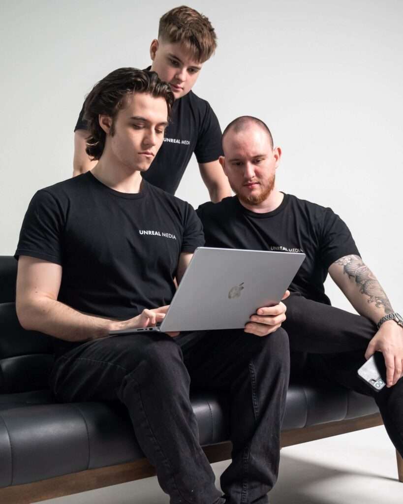 Unreal Media social media marketing Brisbane team sitting together on a couch, collaborating on campaign strategy.