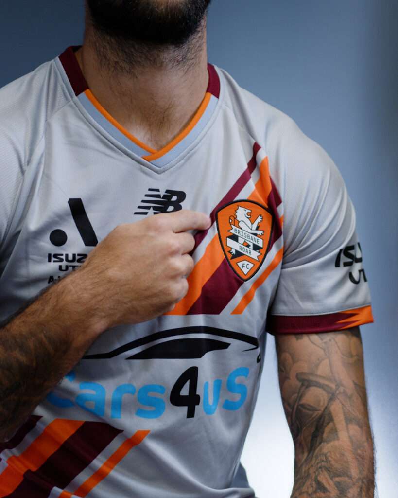 Charlie Austin pointing to Brisbane Roar logo on shirt during New Balance Kit Launch.