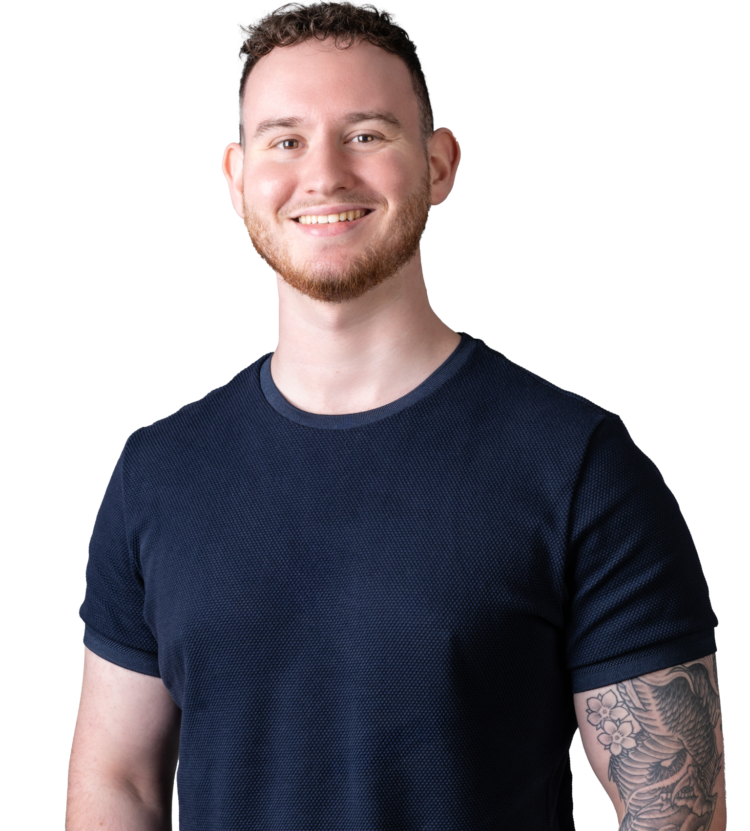 Smiling young entrepreneur with a short haircut and a sleeve tattoo standing against a black background, wearing a dark blue textured t-shirt, embodying a professional yet approachable image.